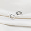 a pair of silver rings sitting on top of a white cloth