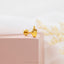 a pair of yellow gold earrings on a pink box