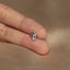 a person's hand holding a tiny diamond ring