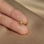a person's hand holding a tiny gold ring