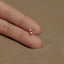 a person's hand holding a tiny red and white heart shaped stud