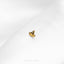 a single gold earring on a white surface