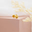 a pair of gold earrings sitting on top of a pink box