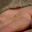 a person's hand holding a tiny gold bird ring