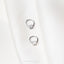 a pair of earrings sitting on top of a white shirt