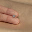 a person's hand holding a small diamond ring