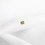 a gold heart pin sitting on top of a white sheet