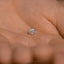 a person's hand holding a small diamond ring
