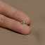 a person's hand holding a tiny silver bead