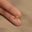 a person's hand holding a tiny gold ring
