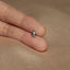 a person's hand holding a tiny silver ring