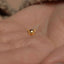 a person's hand with a tiny gold nose ring