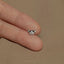 a person's hand holding a tiny diamond ring