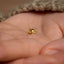 a tiny gold cat earring on someone's hand