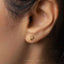 a close up of a person's ear wearing a gold earring