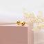 a pair of gold earrings sitting on top of a pink box