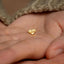 a small gold heart shaped earring on a person's hand