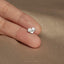 a person's hand holding a tiny heart shaped ring