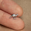 a small silver kangaroo brooch sitting on top of a person's finger