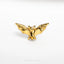 a gold bat pin sitting on top of a white surface