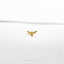 a small gold bird brooch sitting on top of a white surface