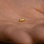 a tiny gold object sitting on top of a person's hand