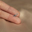 a person's hand holding a tiny dinosaur ring