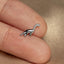 a small silver dinosaur brooch sitting on top of a person's finger