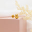 a pair of gold owl earrings sitting on top of a pink box