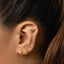 a close up of a person wearing a pair of gold ear piercings