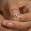 a woman&#39;s hand holding a silver ring with a fish on it