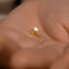 a person&#39;s hand holding a tiny gold earring