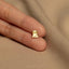 a person&#39;s hand holding a small gold ring