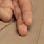 a person&#39;s hand holding a tiny gold ring