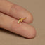 a person&#39;s finger with a tiny gold gun ring on it