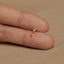 a person&#39;s hand holding a tiny gold arrow ring