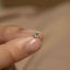 a person holding a tiny diamond ring in their hand