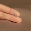 a person&#39;s hand holding a tiny silver animal ring