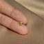 a person&#39;s hand holding a tiny gold ring