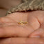 a person holding a tiny gold ring in their hand