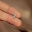 a person&#39;s hand holding a tiny silver leaf ring