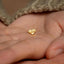 a small gold heart shaped earring on a person&#39;s hand