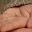 a person holding a tiny gold bird in their hand