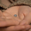a person's hand holding a tiny silver bead