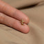 a person&#39;s hand holding a tiny gold ring