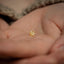 a close up of a person's hand holding a small gold bead