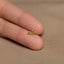 a person's hand holding a tiny gold ring
