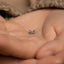 a person's hand holding a tiny bow tie ring