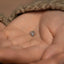 a person's hand holding a tiny diamond ring