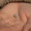 a tiny silver bird pin sitting on top of a person&#39;s hand